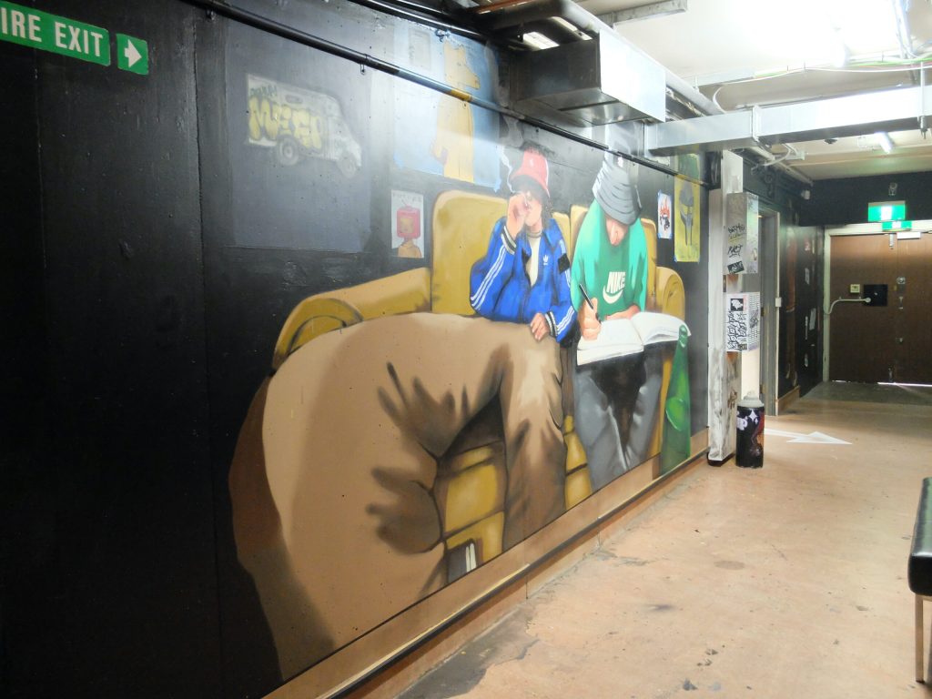 Mural of two artists on a couch at Canterbury Museum