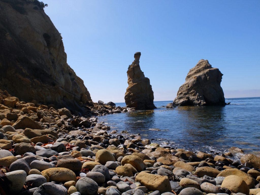 beautiful stoney beach with rock pointing into the sky
